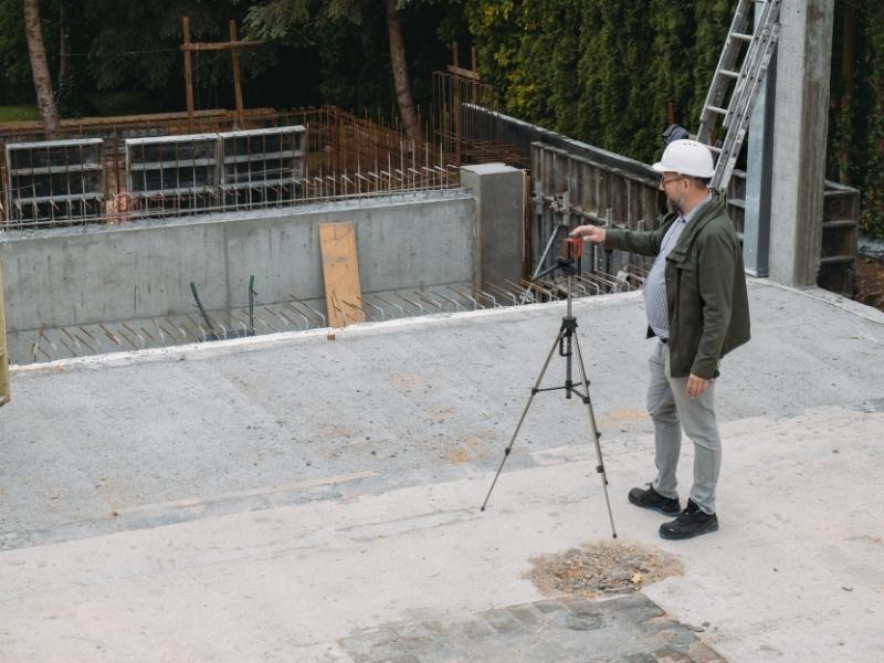 Construction surveyor verifying foundation layout accuracy at an active building site.